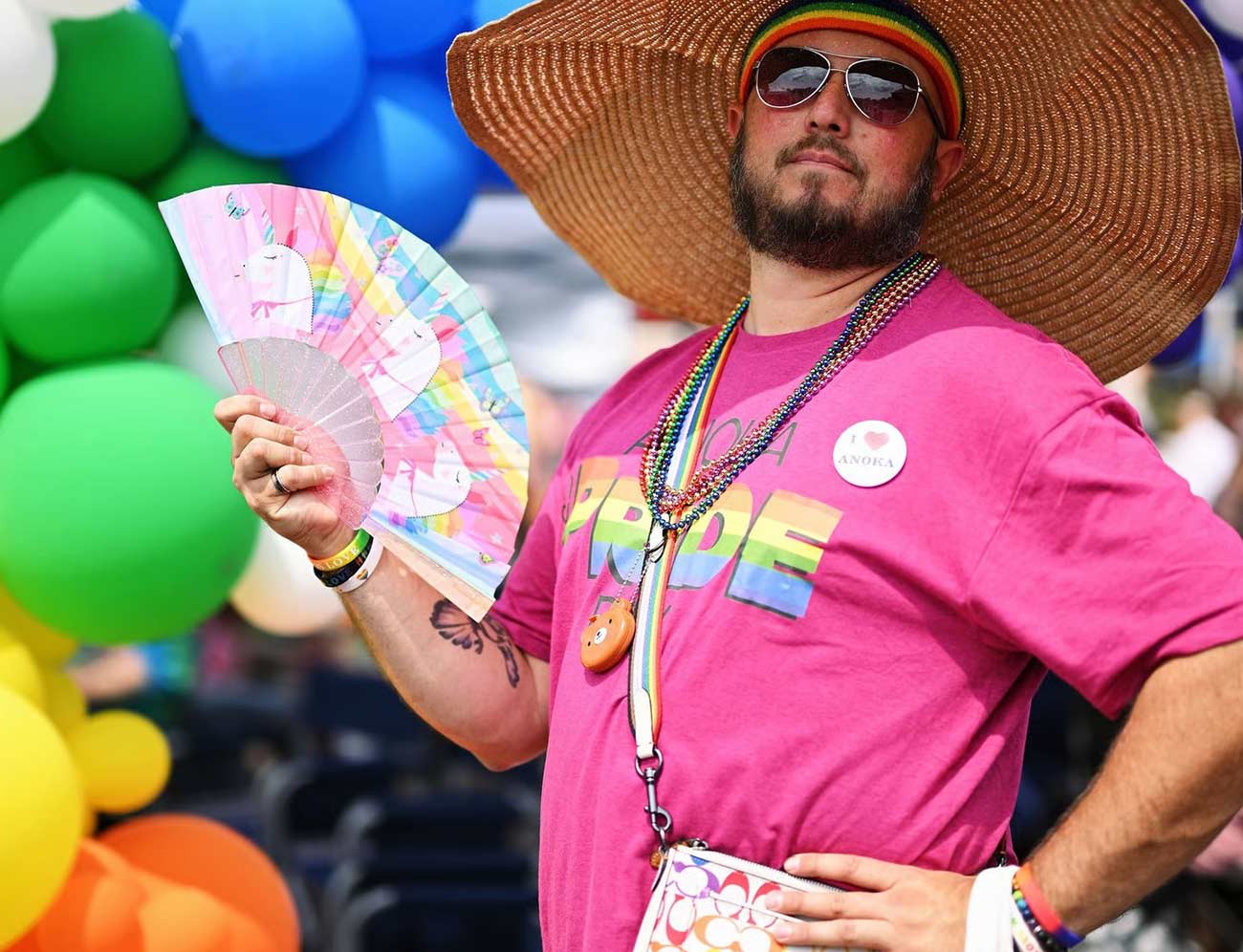 Man at Anoka Pride sports a Unicorn fan with pastel rainbow colors.