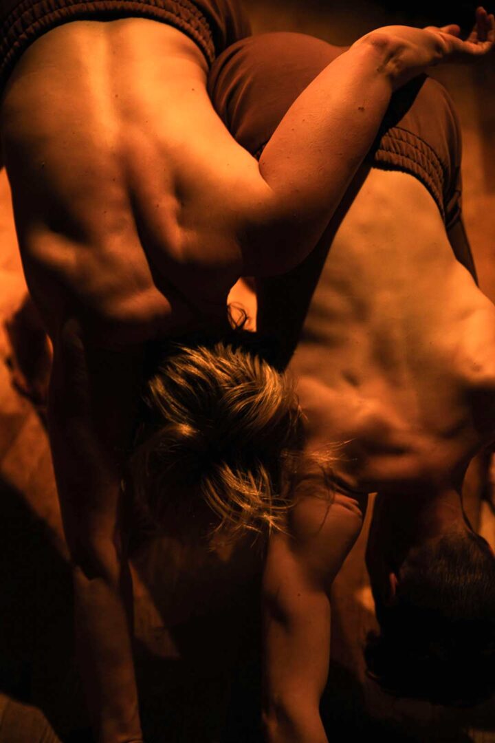 Close-up of the A Body (Un)Becoming performers bending over each others backs.