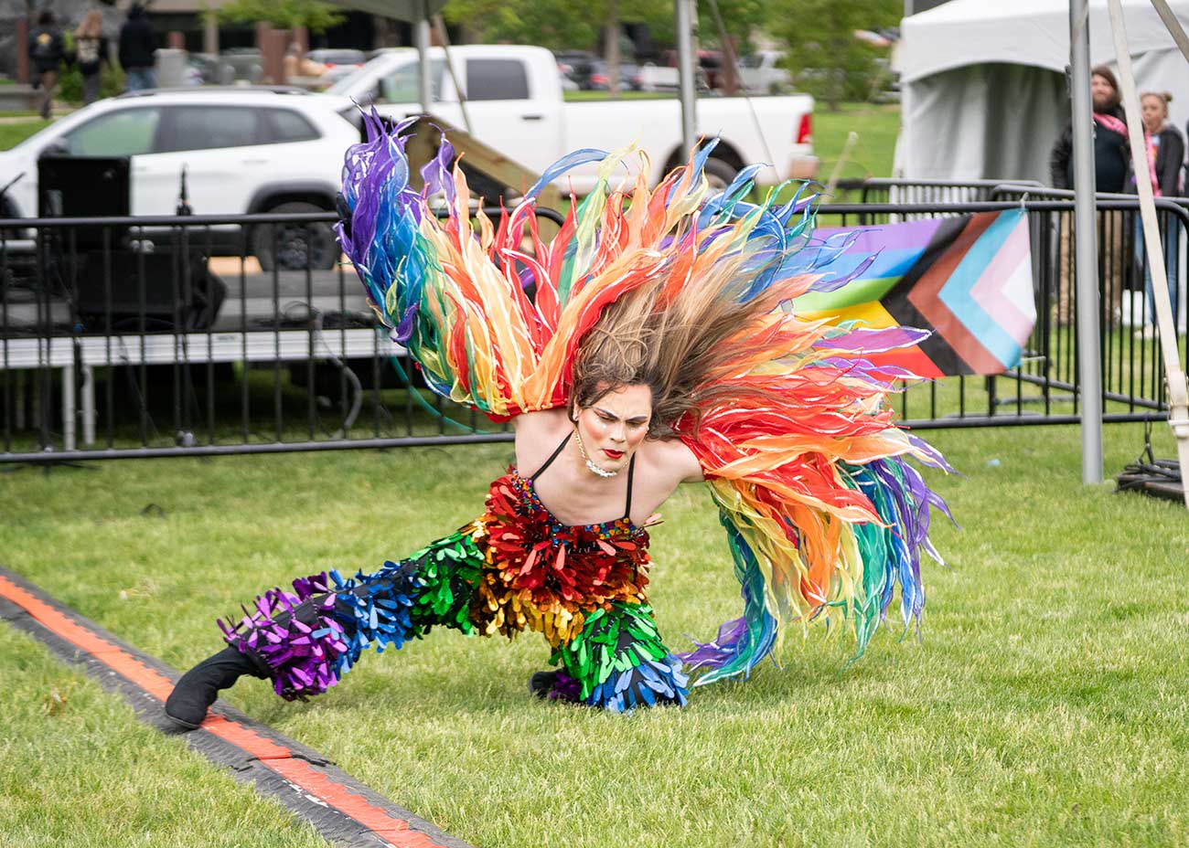 Dancer with rainbow wings flares them in the air during dance.
