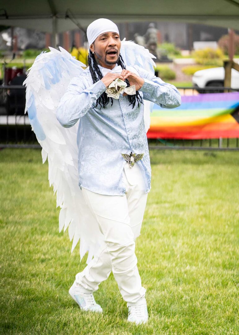 Drag King performer dances for tips in a heavenly outfit with white angel wings.