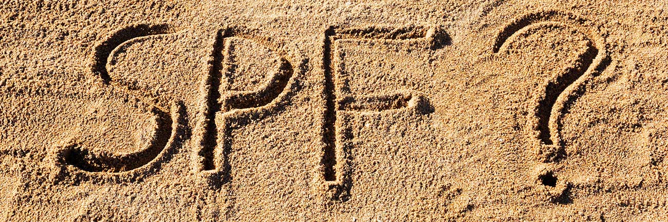 Sun protect factor (SPF) word written in sand on the beach with question mark.