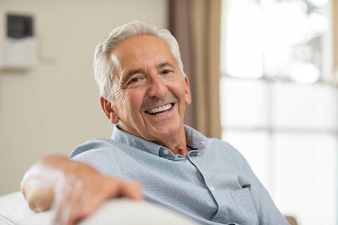 Old man relaxing on sofa and looking at camera.